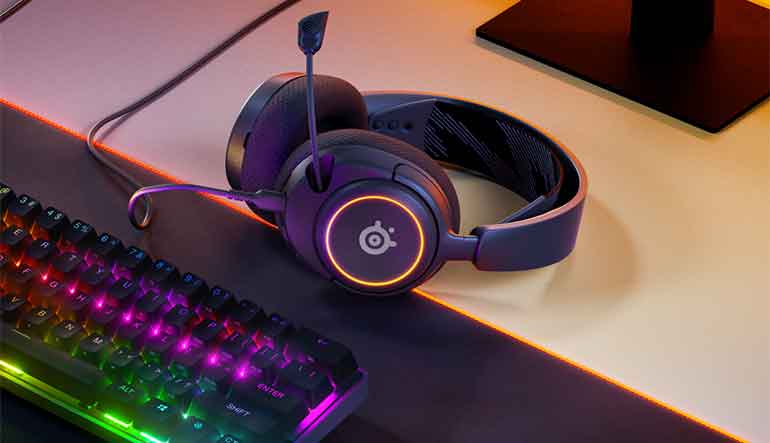 Recensione SteelSeries Arctis Nova 3: l'auricolare poggia su una scrivania accanto alla tastiera.